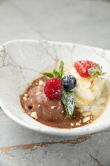 ice cream, chocolate, vanilla with berries on a gray table

