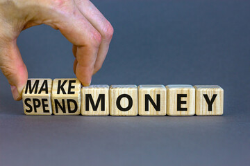 Spend or make money symbol. Businessman turns cubes and changes concept words Spend money to Make money. Beautiful grey table grey background. Business spend or make money concept. Copy space.