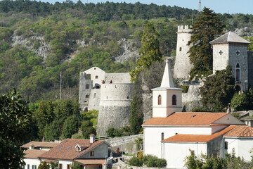 Fototapeta na wymiar View on Trsat Castle and churh in Rijeka from opposite hill. It lies at the exact spot of an ancient Illyrian and Roman fortress and is surround by tress and buildings.