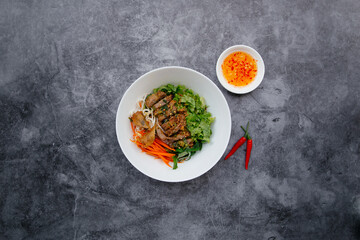 Fried Roll Noodle With BBQ Pork, fish sauce and salad served in bowl isolated on dark grey background top view of japanese food