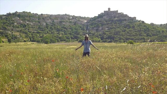 persona con cappello che cammina sola  in un campo di grano in campagna 