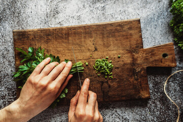 a man cuts parsley with his hands on a brown wooden board for salads or other dishes 1