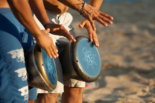 2 hombres tocando tambores en la playa