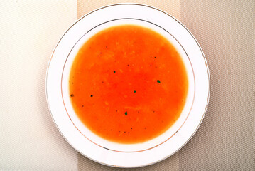 Homemade pumpkin cream soup with carrots in the white plate. Top view. Healthy diet concept.