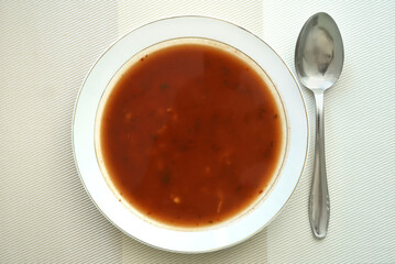 Homemade tomato soup with dough pellets and parsley leaves in the white plate. Top view. Healthy diet concept. 