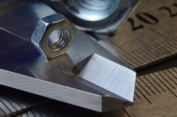 Accurate measuring tool caliper and metal ruler lie in place with nuts. close-up.