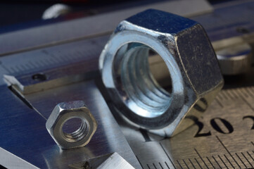 Accurate measuring tool caliper and metal ruler lie in place with nuts. close-up.