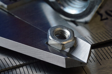 Accurate measuring tool caliper and metal ruler lie in place with nuts. close-up.