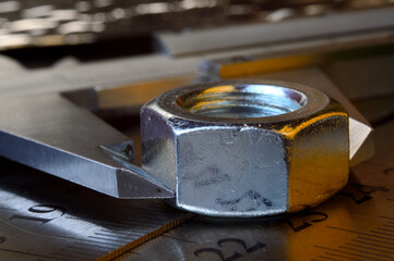 Accurate measuring tool caliper and metal ruler lie in place with nuts. close-up.