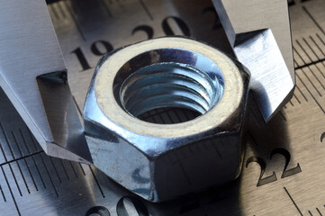 Accurate measuring tool caliper and metal ruler lie in place with nuts. close-up.