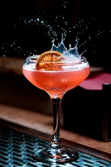 Foto op Plexiglas Lemon garnish splashing in pink craft cocktail coupe glass © Craig