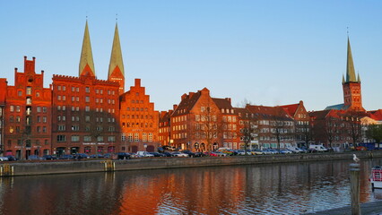 Fototapeta na wymiar historische Häuserfassaden und Kirchtürme in Lübeck entlang der Trave im Abendlicht