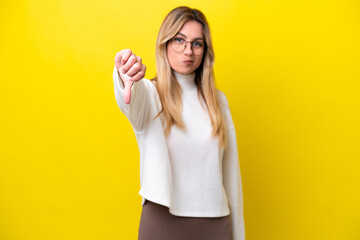 Young Uruguayan woman isolated on yellow background showing thumb down with negative expression