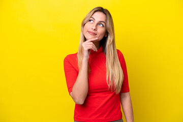 Young Uruguayan woman isolated on yellow background looking up while smiling