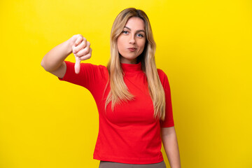 Fototapeta premium Young Uruguayan woman isolated on yellow background showing thumb down with negative expression