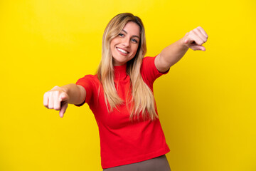 Young Uruguayan woman isolated on yellow background pointing front with happy expression
