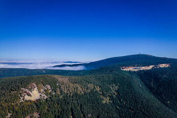 Aerial landscape of the green mountains in a daylight. Clouds low over the peaks, clear blue sky.