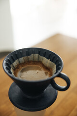 Close-up of fragrant hot coffee in black ceramic cup on table.