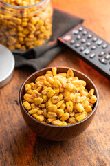 Roasted salted corn snack in bowl on wooden table.