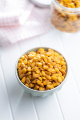 Roasted salted corn snack in bowl on white table.