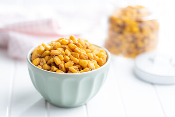 Roasted salted corn snack in bowl on white table.