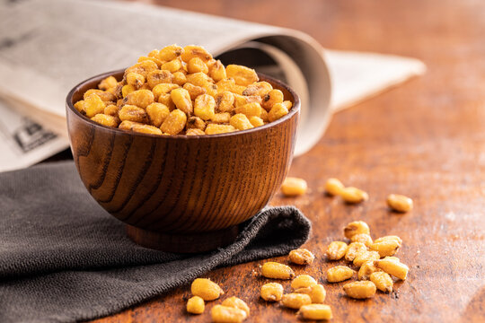 Roasted salted corn snack in bowl on wooden table.