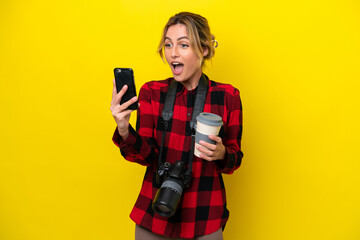 Uruguayan photographer woman isolated on yellow background holding coffee to take away and a mobile