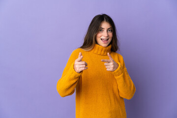 Fototapeta na wymiar Young caucasian woman isolated on purple background pointing to the front and smiling