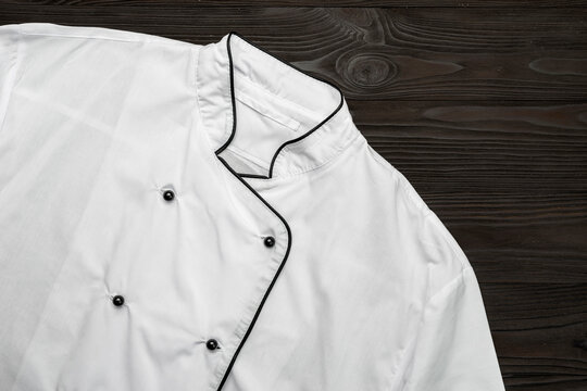 Cook clothes, chef-cooker's jacket, chef's outfit on a wooden board table. Abstract kitchen background for advertising