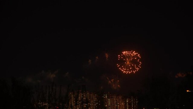 Fireworks in the night sky over houses. Festive fireworks on dark background of night sky over houses with illumination.
