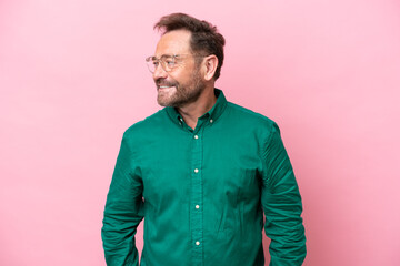 Middle age caucasian man isolated on pink background looking to the side and smiling