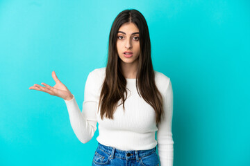 Fototapeta premium Young caucasian woman isolated on blue background making doubts gesture