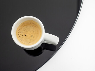 A cup of coffee on a black glass table