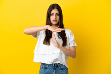 Young caucasian woman isolated on yellow background making time out gesture