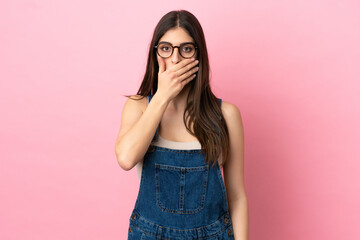 Fototapeta premium Young caucasian woman isolated on pink background covering mouth with hand