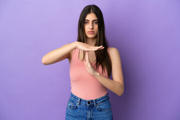 Young caucasian woman isolated on purple background making time out gesture