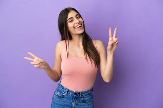 Young caucasian woman isolated on purple background showing victory sign with both hands