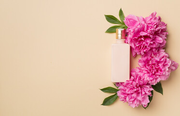 Cosmetic bottle with peony flower and comb on color background, top view