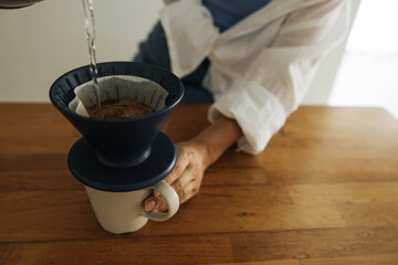 Close-up of fair-skinned woman serving hot coffee in living room of her house morning.