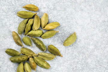 Top view of green cardamom seed pods on a gray background