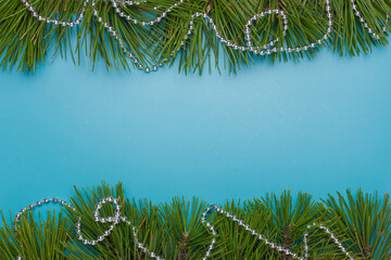 Merry Christmas, Happy New Year festive postcard, template, blue background, pine tree branches frame, silver beads. Copy space