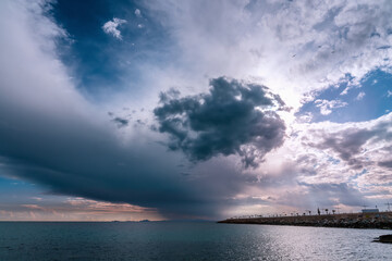 Obraz premium Scenic rain and dark dramatic stormy clouds over sea partly cover skies