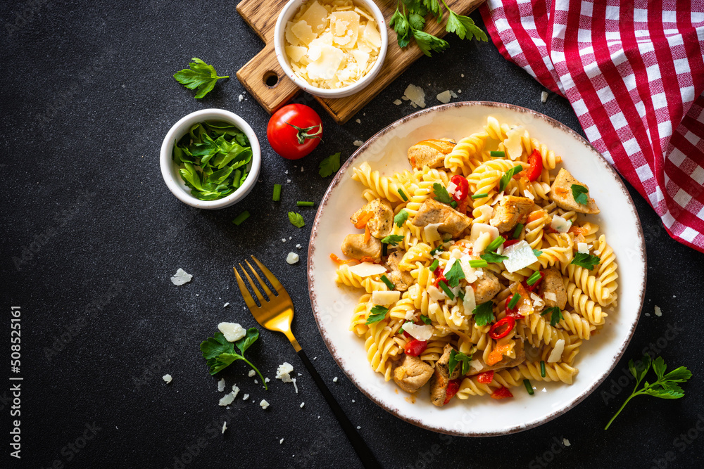 Sticker pasta with turkey meat, vegetables and parmesan on dark stone table. top view with space for recipe.