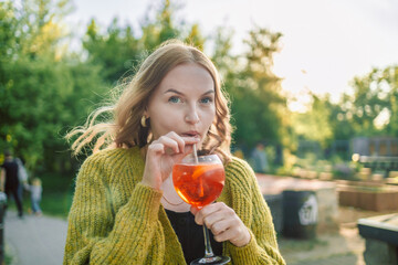 Closeup image of happy European 30s blonde woman having fun in cafe and drinking fruit cocktails with pleasure, outfit chilling in restaurant or street cafe - Powered by Adobe