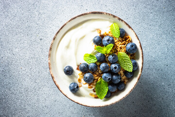 Yogurt with granola and fresh blueberry decorated mint leaves. Healthy breakfast. Top view.