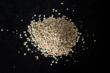 Top view of organic oats in a pile on dark moody background.