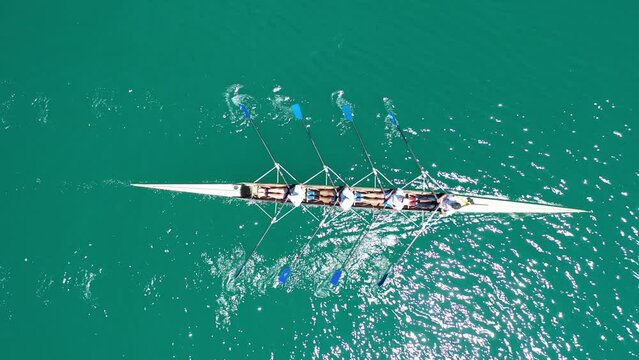 Aerial drone top down video of sport canoe operated by team of young women in emerald clear waters