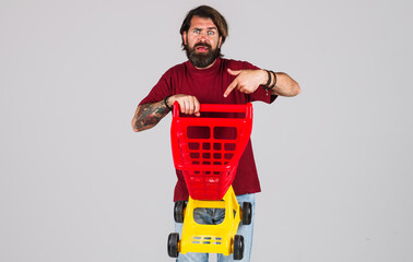 Bearded man pointing with finger on empty shopping cart. Sale. Discount. Black friday. Buying spree.