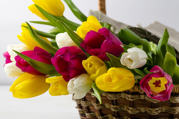 Obraz premium Basket with a bouquet of colored tulips on a white background