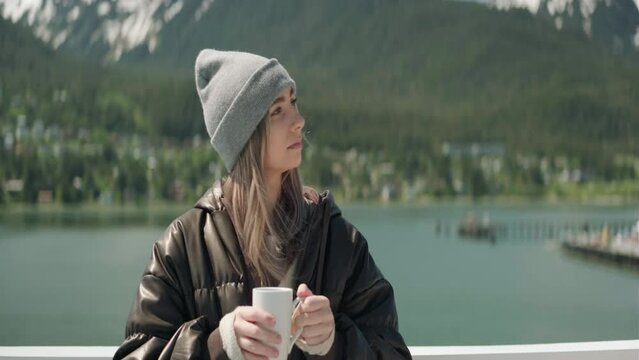 Blond woman sipping warm drink wearing a beenie in Alaska (Anamorphic)